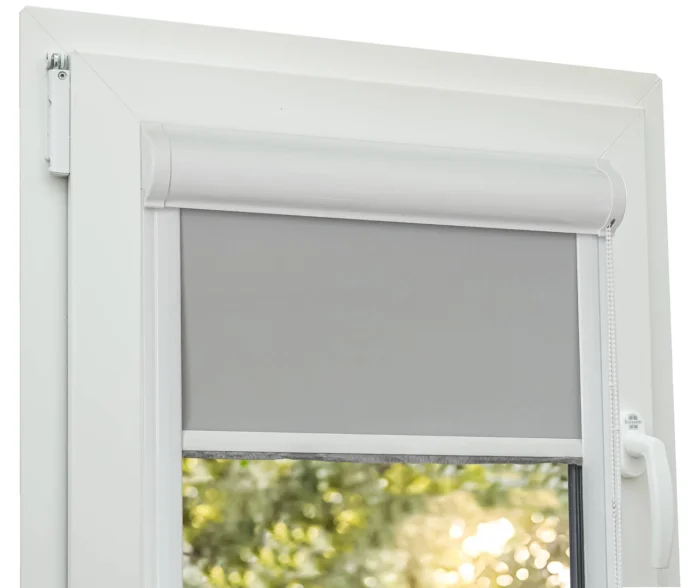 Roleta gri deschis, blackout 100%, cu caseta si ghidaj montata pe tamplarie alba din PVC